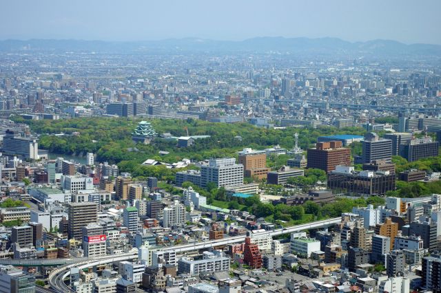 北東方向には豊かな緑に囲まれた名古屋城と官公庁の建物が並ぶ。下端には円頓寺、奥には県営名古屋空港。