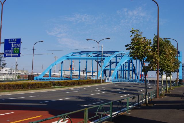 品川埠頭方向に向かうと、運河を渡る青くて大きな「品川ふ頭橋」がある。橋の向こうには車両基地に向かう新幹線が走っていた。