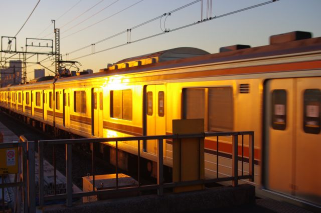 夕陽に輝く京葉線（武蔵野線車両）がホームに入ってきた。