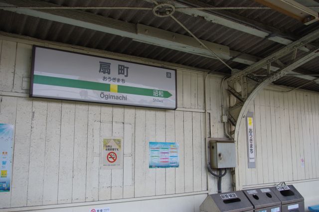 駅名の表示。壁や屋根は他の駅と同じような古びた造り。広告は鶴見大学ばかり。