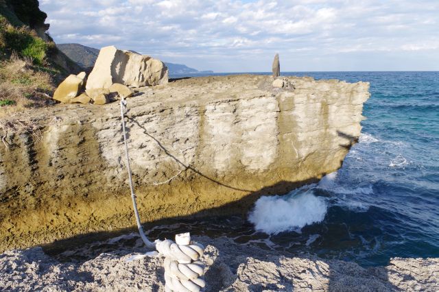 波が強く打ち寄せる隣の岩へ綱が渡されている。