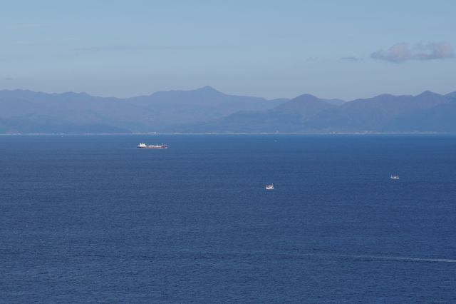 津軽海峡を行き交う船と、遠くに山並みと町並み。