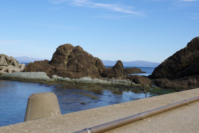 帯島の岩越しに北海道の松前半島が見えます。