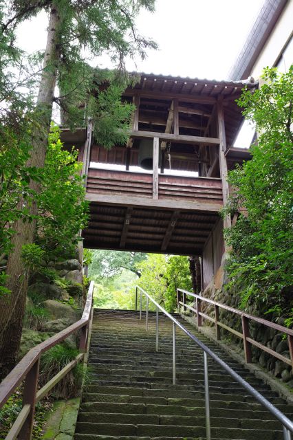 階段の上には２つの建物をつなぐ廊下に「招福の鐘」。