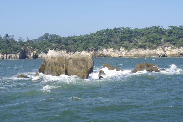 生々しい岩の島と、激しく打ち寄せる波。