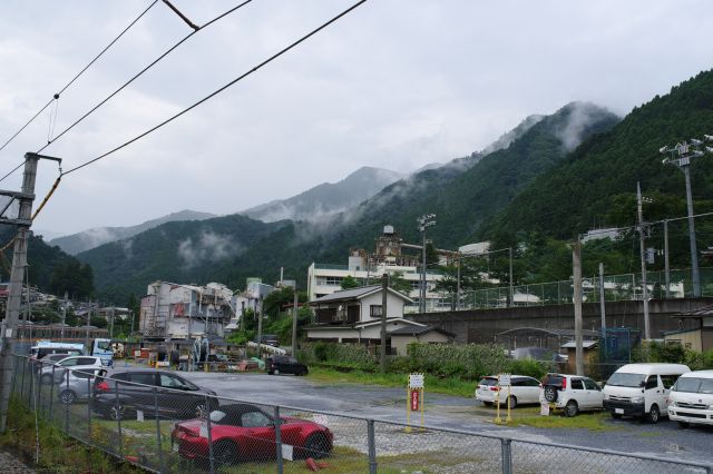 ホームの東側は駐車場と小学校、奥には霧の山並み。