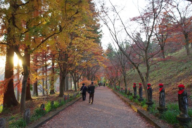 石仏に囲まれた紅葉の路、和風の幻想的で美しい情景です。