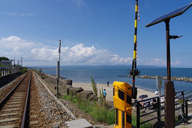 踏切と線路と能登半島と雲の景色。