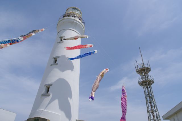 空へと伸びる白い灯台と鯉のぼり。
