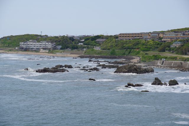 海に向けて建つホテル群、岩場では白い波しぶきが立つ。