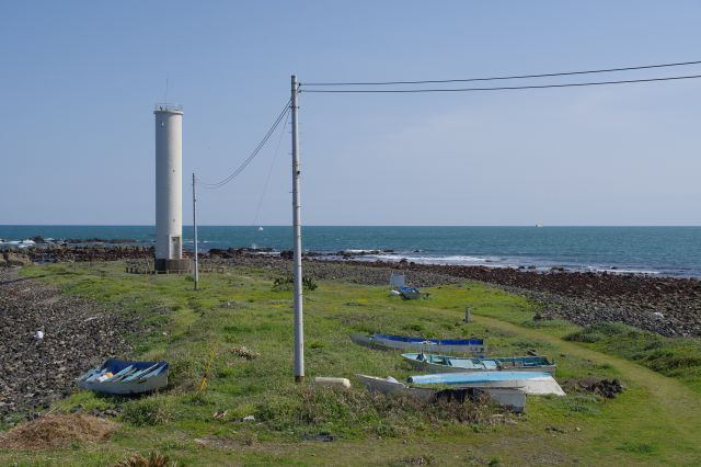円柱の灯台は「長崎鼻一ノ島照射灯」、一ノ島の岩礁を固定的に照らしています。船が置かれた荒涼とした雰囲気や水平線も良い情景。