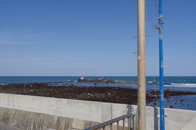 磯が続く海岸沿い、奥に続く太陽の青い水平線。宝満という岩場があります。