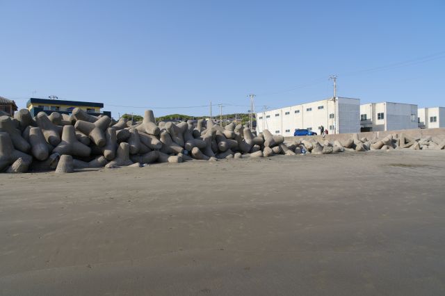 奥行きのある砂浜、道路の先に建物。